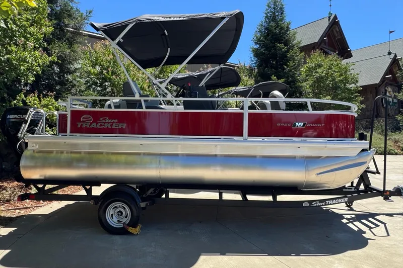 Slide: The Image of 2026 Sun Tracker Bass Buggy 18 DLX pontoon boat on trailer, parked outdoors. - 87