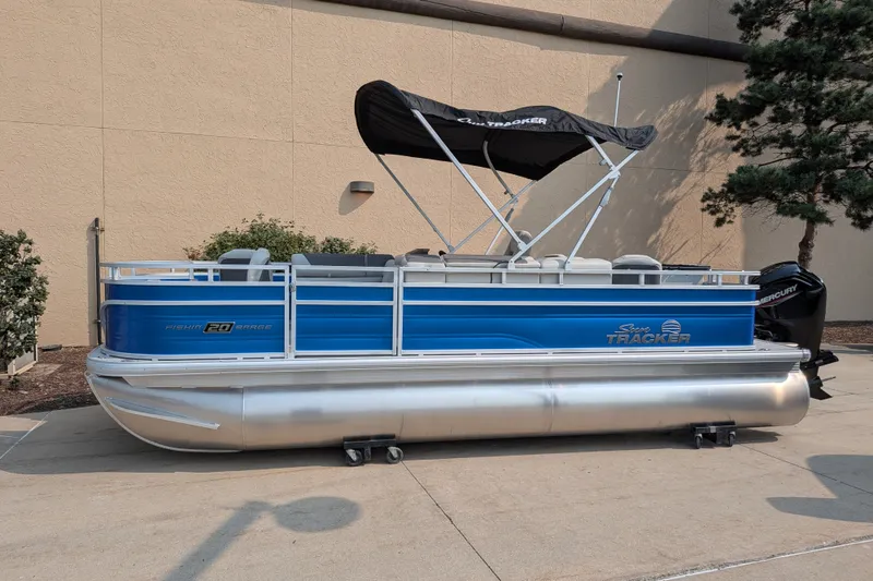 The Image of 2026 Sun Tracker Fishin' Barge 20 DLX pontoon boat with canopy, parked outdoors. - 0