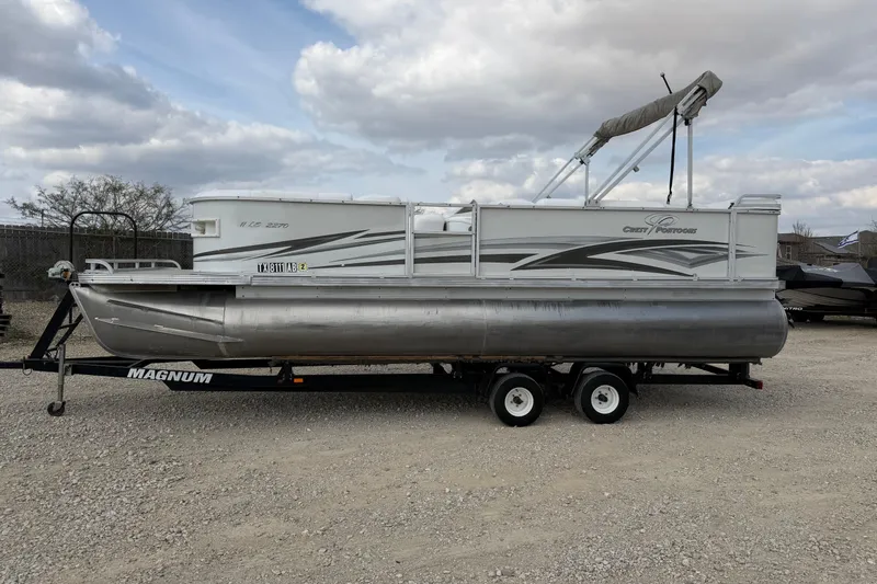 The Image of 2006 Crest II LE 2270 pontoon boat on trailer under cloudy sky. - 0