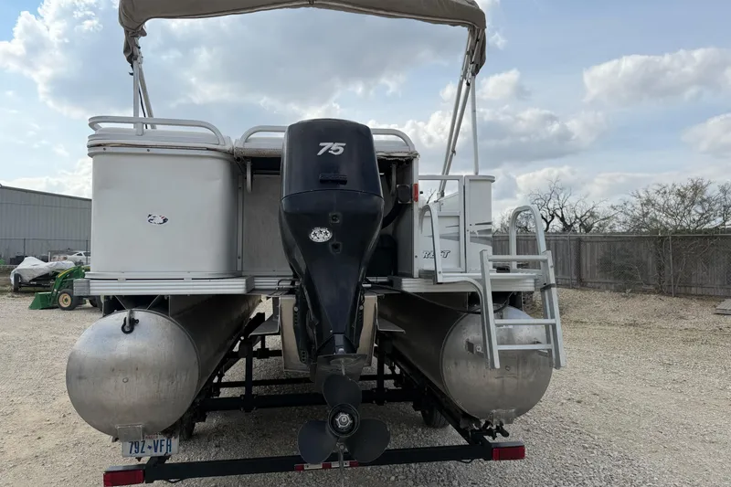 Slide: The Image of 2006 Crest II LE 2270 pontoon boat with 75 HP motor, parked on gravel. - 2