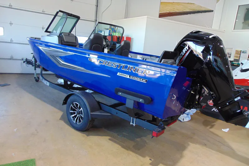 The Image of 2026 Crestliner 1850 Kodiak WT boat in showroom, blue exterior, on trailer. - 2