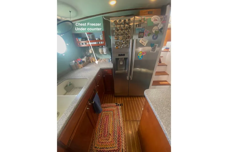 Slide: The Image of 2008 Great Harbour N37 kitchen with stainless steel fridge, wooden cabinets, and under-counter chest freezer. - 5