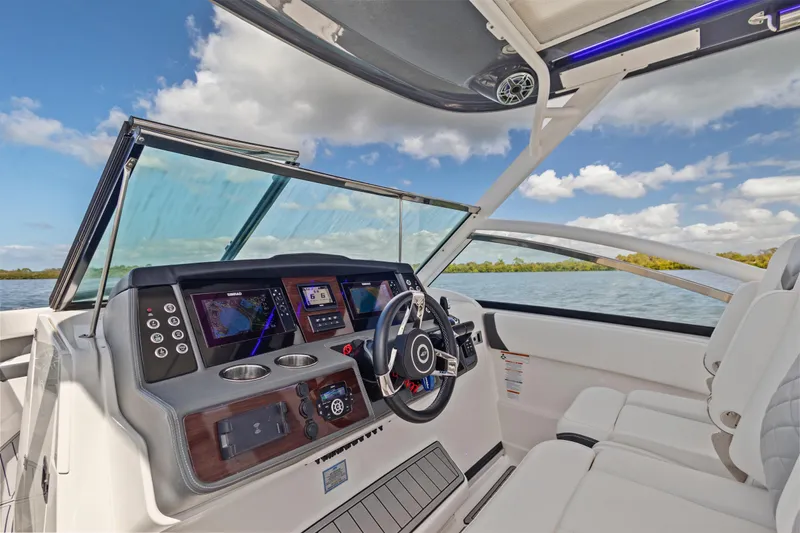 Slide: The Image of 2022 Chaparral 300 OSX boat cockpit with modern dashboard and steering wheel on open water. - 16
