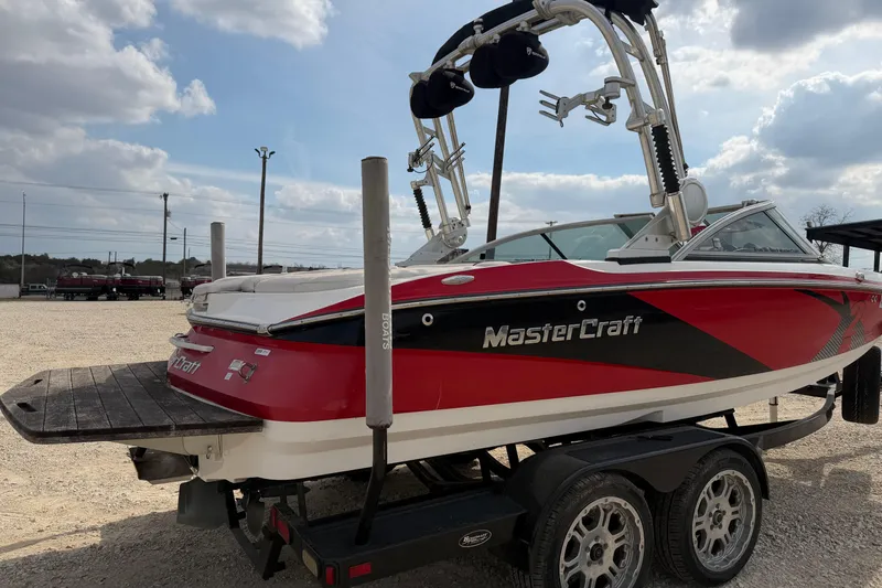Slide: The Image of 2012 MasterCraft X2 boat on trailer, red and black design, parked outdoors. - 4