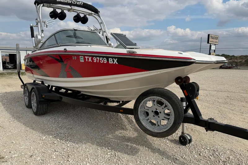 Slide: The Image of 2012 MasterCraft X2 boat on trailer, red and white design, parked outdoors. - 5