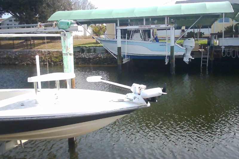 Slide: The Image of 2012 Sterling 220XS boat docked near a covered marina, with calm water. - 46