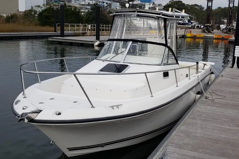 Slide: The Image of 2005 Shamrock 246 Adventurer boat docked at marina, featuring sleek white design. - 0