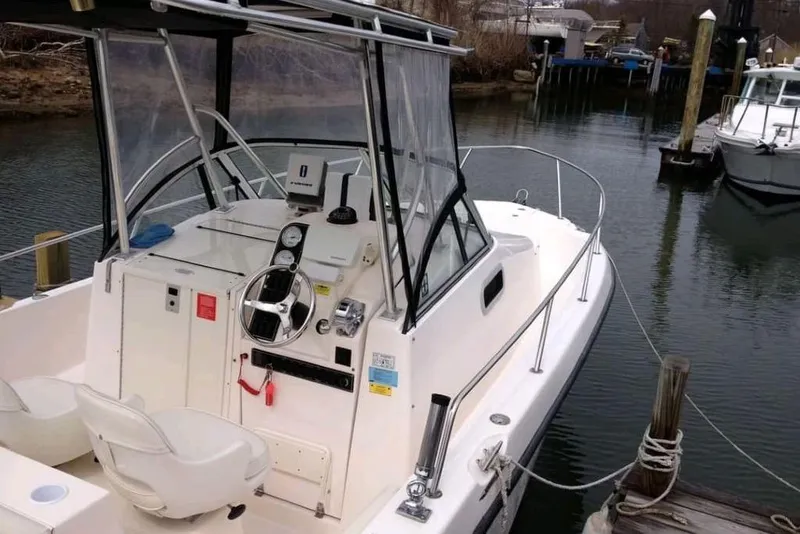 Slide: The Image of 2005 Shamrock 246 Adventurer boat docked, featuring helm and seating area. - 2