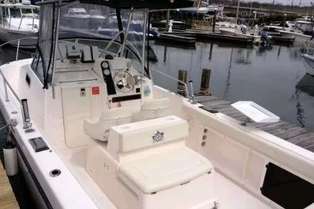 Slide: The Image of 2005 Shamrock 246 Adventurer boat docked at marina, featuring spacious cockpit and helm. - 5