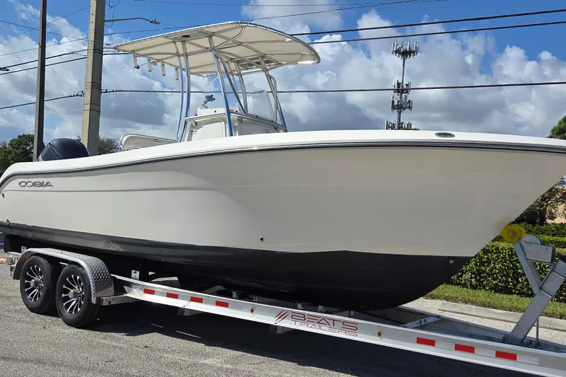 The Image of 2020 Cobia 237 Center Console boat on trailer under blue sky. - 0
