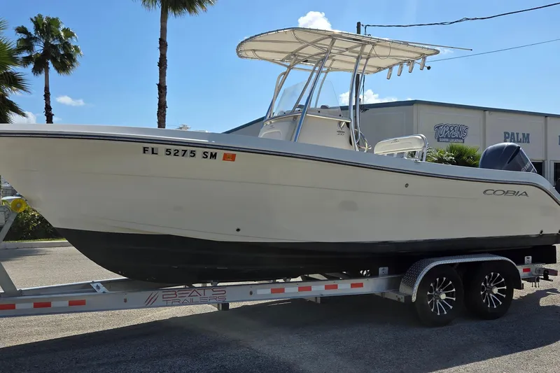 Slide: The Image of 2020 Cobia 237 Center Console boat on trailer, parked outdoors under clear sky. - 2