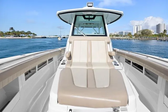 Slide: The Image of 2019 Sailfish 360 CC boat with beige seating, cruising on a sunny day near a city skyline. - 21
