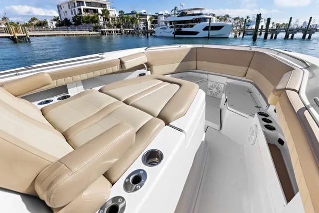 Slide: The Image of 2019 Sailfish 360 CC boat interior with beige seating, cup holders, and waterfront view. - 23