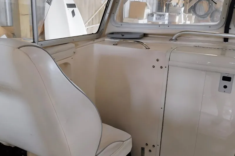 Slide: The Image of Interior of a 2009 McKee Craft 28 boat, featuring white seating and cabin details. - 10