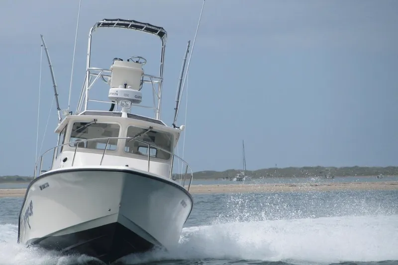 Slide: The Image of 2009 McKee Craft 28 boat cruising on open water with a clear sky backdrop. - 16