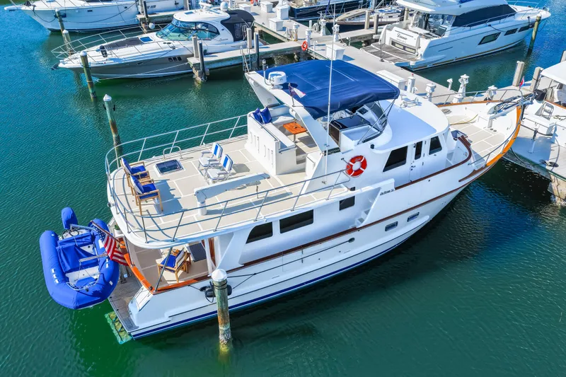Slide: The Image of 2008 DeFever 52 Euro yacht docked at marina, featuring spacious deck and blue canopy. - 17