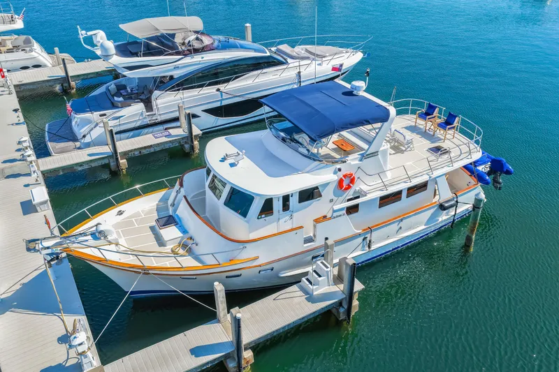Slide: The Image of 2008 DeFever 52 Euro yacht docked at marina, featuring spacious deck and blue canopy. - 3