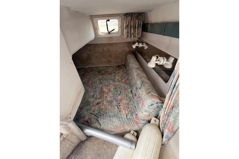 Slide: The Image of 1996 Rinker Fiesta Vee 265 cabin interior with floral upholstery and small window. - 7