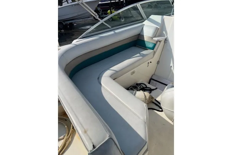 Slide: The Image of Interior seating of a 1996 Rinker Fiesta Vee 265 boat, featuring white and teal upholstery. - 9