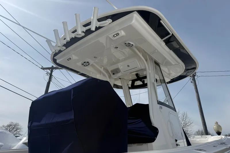 Slide: The Image of 2024 Regulator 28 Forward Seating boat with T-top and rod holders under clear sky. - 11