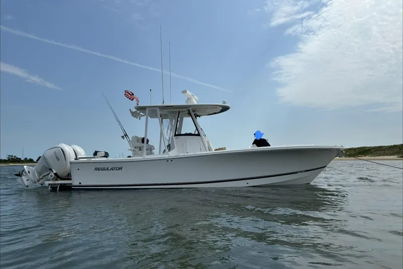 Slide: The Image of 2024 Regulator 28 Forward Seating boat on water, side view with clear sky. - 2