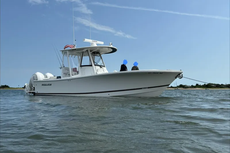 Slide: The Image of 2024 Regulator 28 Forward Seating boat on calm water under clear sky. - 3