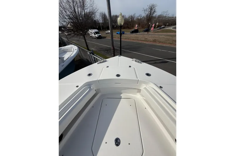 Slide: The Image of 2024 Regulator 28 Forward Seating boat deck view, parked near a road. - 37