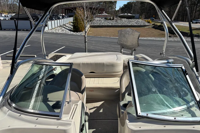 Slide: The Image of 2003 Sea Ray 200 Bow Rider interior with seating and windshield, parked outdoors. - 7