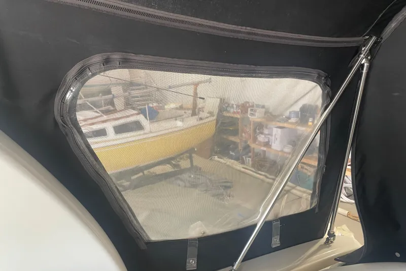 Slide: The Image of 2006 Sea Ray Sundancer 260 interior view with window, showing a yellow boat outside. - 12