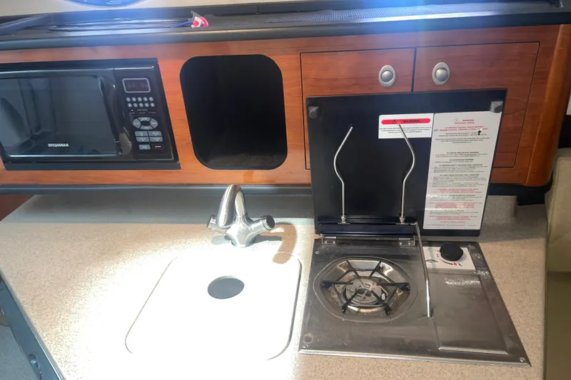 Slide: The Image of 2006 Sea Ray Sundancer 260 galley with microwave, stove, and sink. - 18