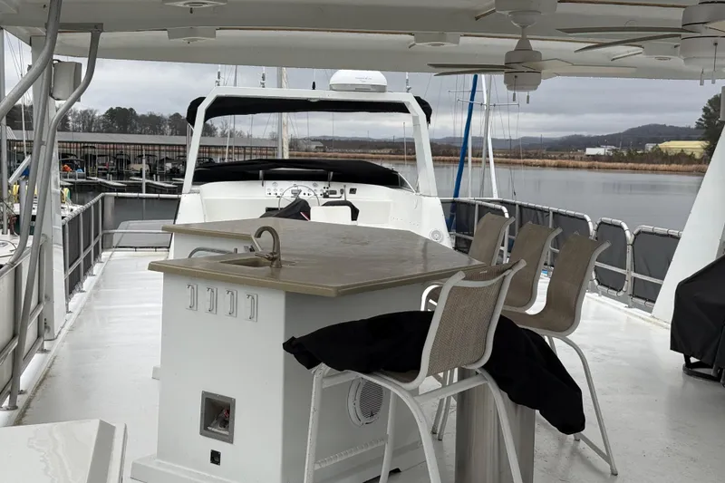 Slide: The Image of Houseboat deck with bar seating, featuring a 2001 Sharpe 80 X 18 model, docked by a serene lake. - 109