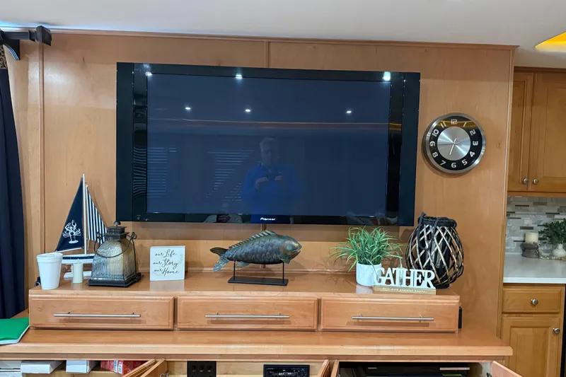 Slide: The Image of Living room with wall-mounted TV, decorative items, and clock on wooden paneling. - 21