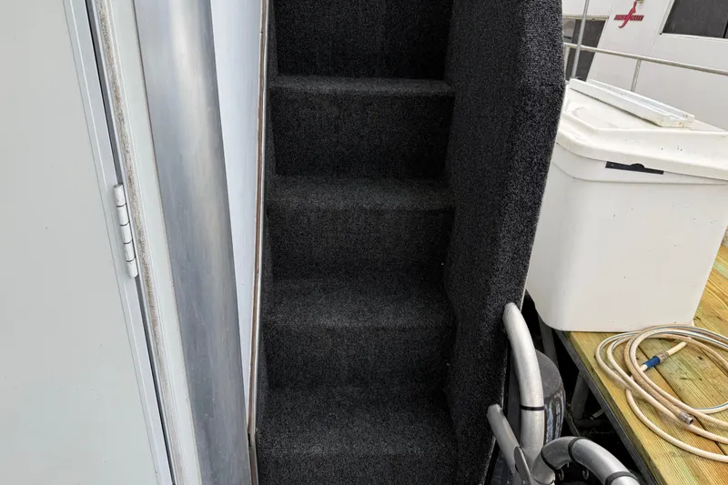 Slide: The Image of Carpeted stairs on a 2001 Sharpe 80 X 18 houseboat, with storage container nearby. - 25