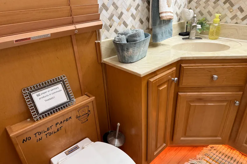 Slide: The Image of Bathroom interior with wooden cabinets, sink, and a sign prohibiting toilet paper use. Sharpe 80 X 18, 2001. - 39