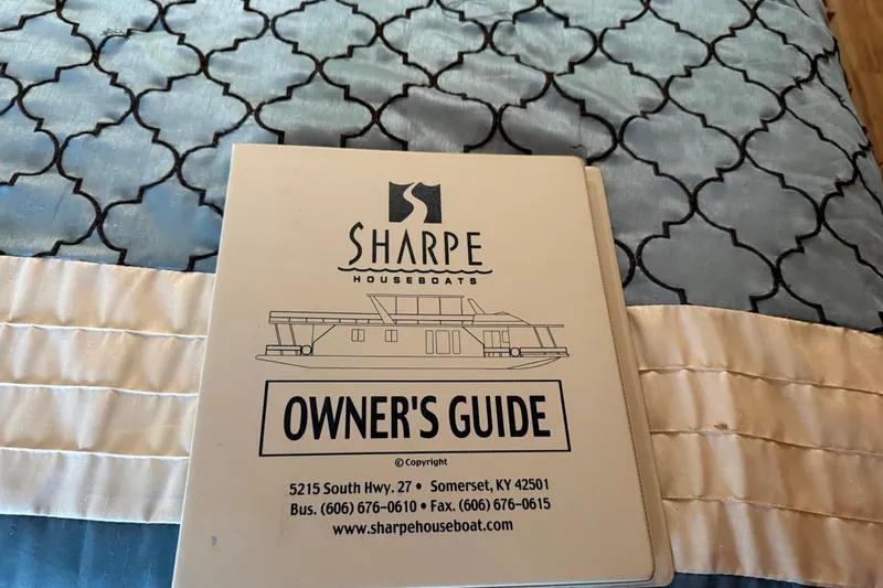 Slide: The Image of Owner's guide for 2001 Sharpe 80 X 18 houseboat on patterned bedspread. - 51
