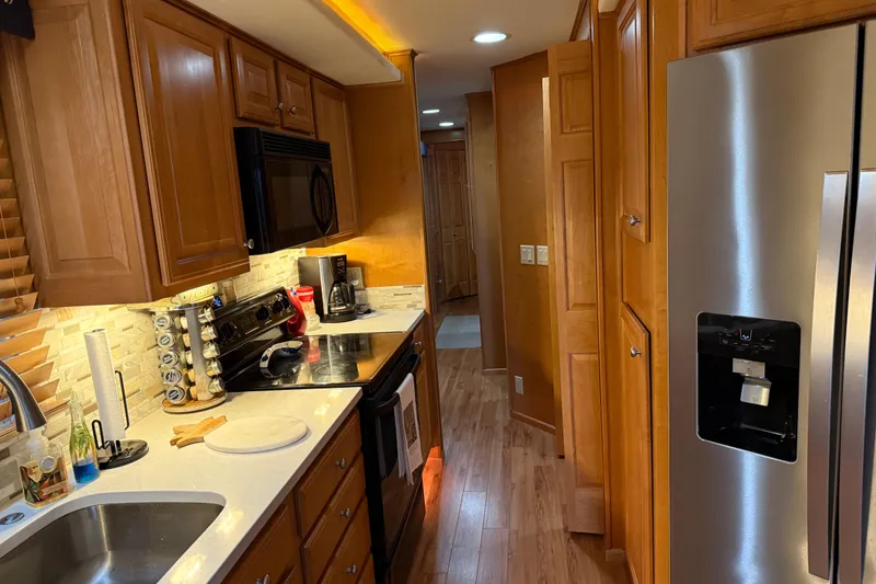 Slide: The Image of Modern kitchen interior in a 2001 Sharpe 80 X 18 houseboat, featuring wooden cabinets and stainless steel appliances. - 88
