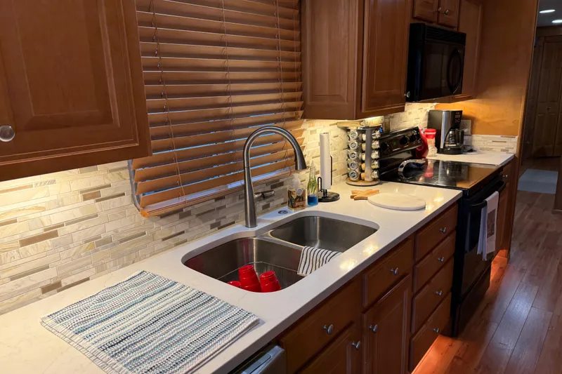 Slide: The Image of Modern kitchen in a 2001 Sharpe 80 X 18 houseboat with wooden cabinets and stainless steel sink. - 90