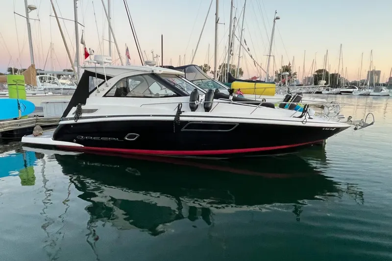The Image of 2014 Regal 35 Sport Coupe docked in a marina, surrounded by sailboats. - 0