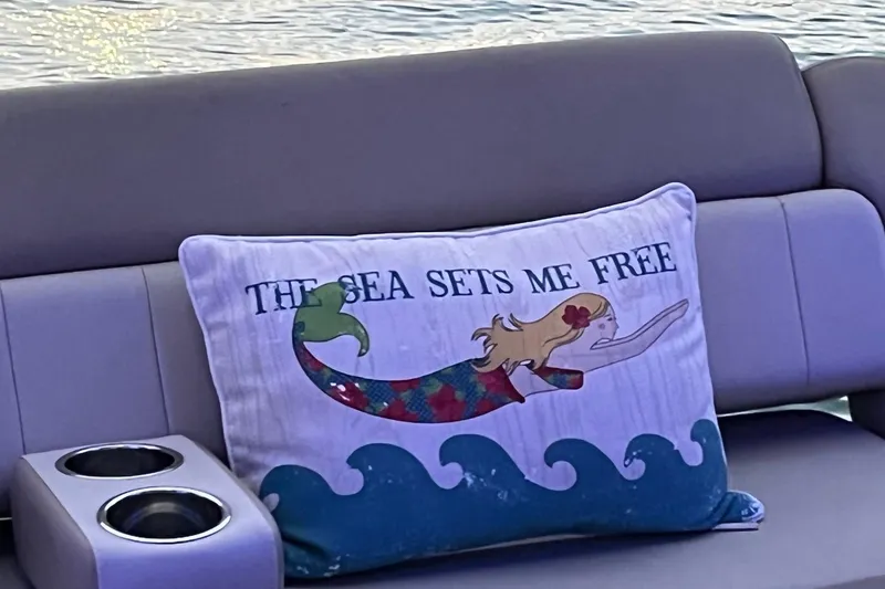 Slide: The Image of 2014 Regal 35 Sport Coupe boat seating with decorative pillows by the water. - 30