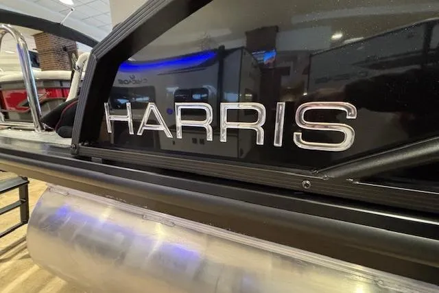 Slide: The Image of 2026 Harris Cruiser 230 boat, close-up of brand logo in showroom. - 2