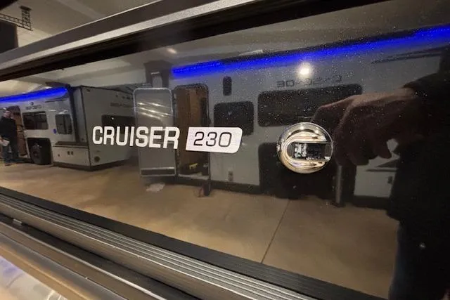Slide: The Image of 2026 Harris Cruiser 230 boat nameplate with reflection of RVs indoors. - 3