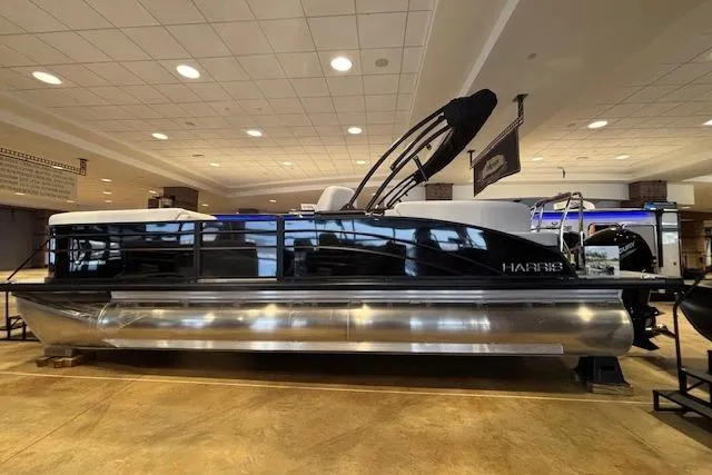 Slide: The Image of 2026 Harris Cruiser 230 pontoon boat displayed indoors, featuring sleek black and silver design. - 6