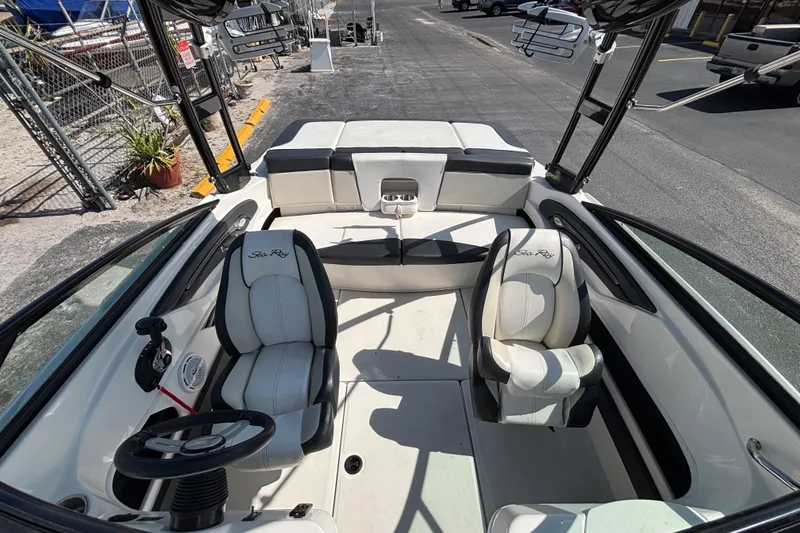 Slide: The Image of 2014 Sea Ray 205 Sport boat interior with seating and steering wheel, docked outdoors. - 27