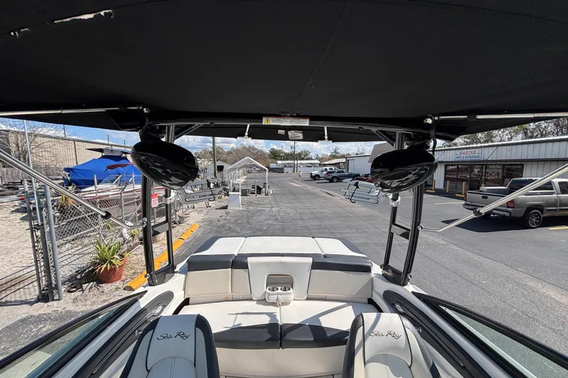 Slide: The Image of 2014 Sea Ray 205 Sport boat interior with canopy and seating, parked in a marina. - 28