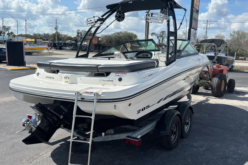 Slide: The Image of 2014 Sea Ray 205 Sport boat on trailer, parked outdoors under a partly cloudy sky. - 3