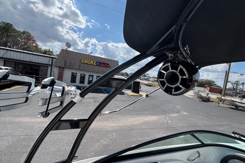 Slide: The Image of 2014 Sea Ray 205 Sport boat with tower speakers, parked near a vape shop. - 30