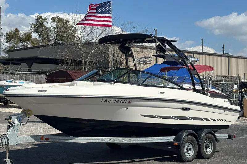 Slide: The Image of 2014 Sea Ray 205 Sport boat on trailer with American flag in background. - 8