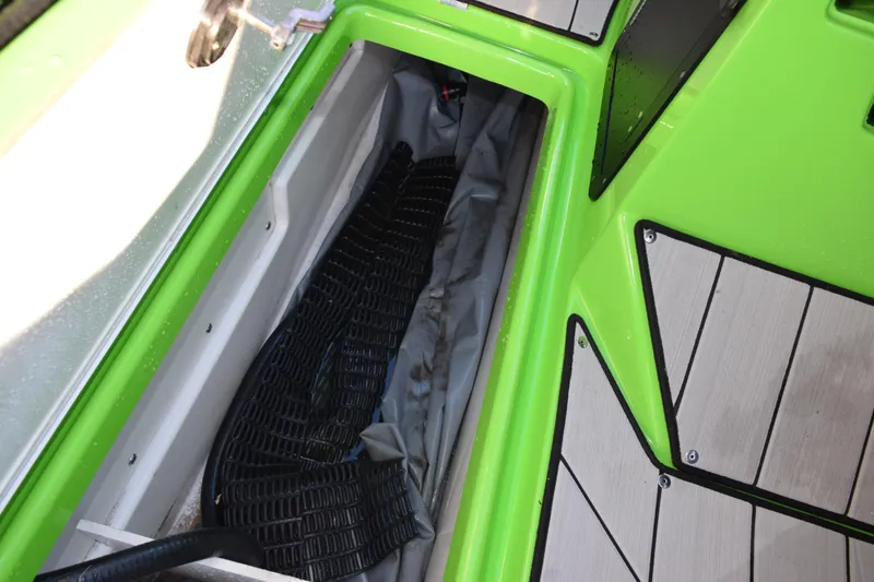 Slide: The Image of Storage compartment in 2022 Yamaha Boats 255XD, featuring vibrant green and gray interior. - 25