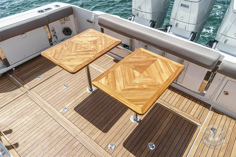 Slide: The Image of Boston Whaler 405 Conquest 2025 deck with wooden tables and outboard motors. - 32