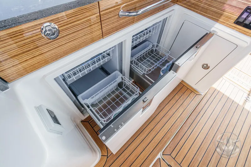 Slide: The Image of 2025 Boston Whaler 405 Conquest interior with open dual-drawer refrigerator, showcasing modern design. - 49